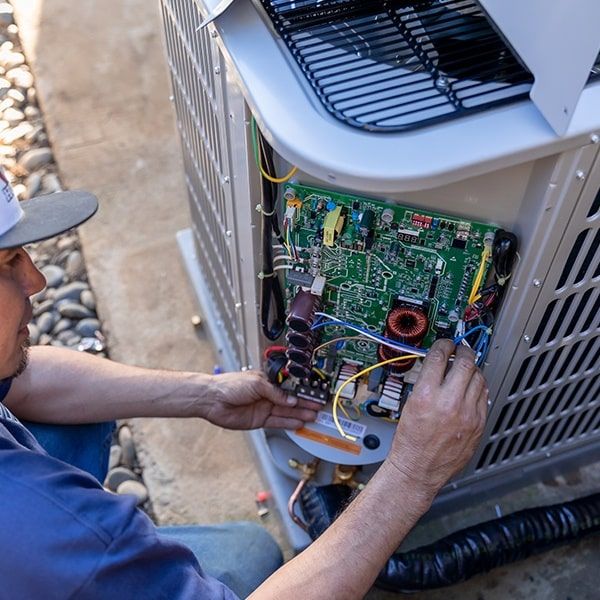 Technician servicing an outdoor air conditioner condenser